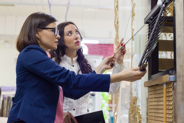 Two women shopping at a window treatment store looking overwhelmed.