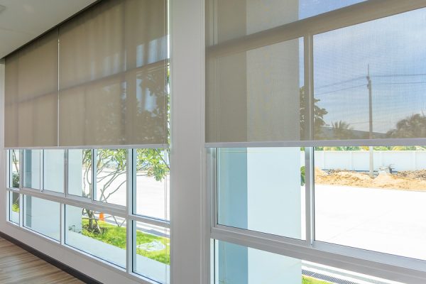 Motorized shades on large banks of windows along a hallway with road and landscaping visible on the outside of the windows.